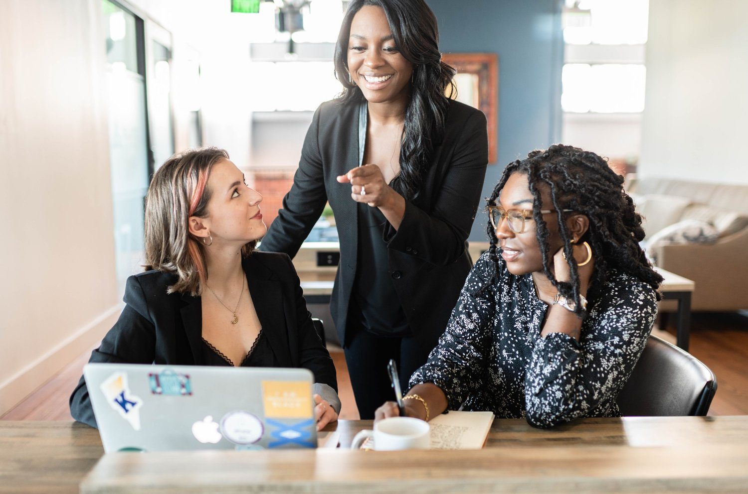 Three women collaborating around a laptop